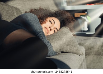 Young woman is taking a nap on a comfortable sofa in the afternoon sun, enjoying a moment of peace and quiet in her living room - Powered by Shutterstock