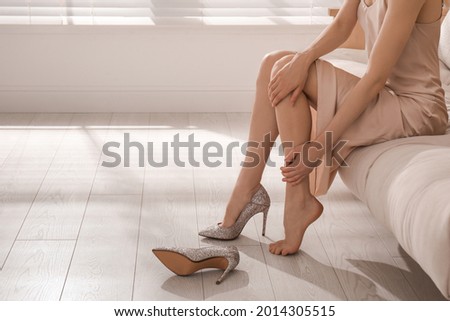 Young woman taking off shoes at home, closeup. Tired feet after wearing high heels