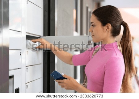 Young woman taking a package out of an automatic mailbox