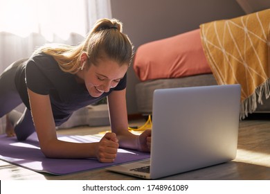 Young Woman Taking Part In Online Fitness Class In Front Of Laptop.