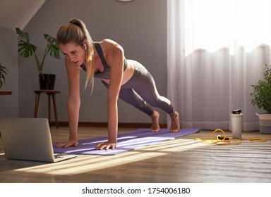 Young Woman Taking Part In Online Fitness Class In Front Of Laptop.