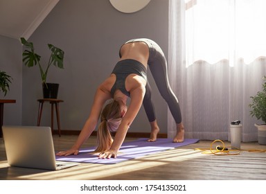 Young Woman Taking Part In Online Fitness Class In Front Of Laptop.