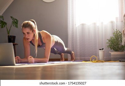 Young Woman Taking Part In Online Fitness Class In Front Of Laptop.