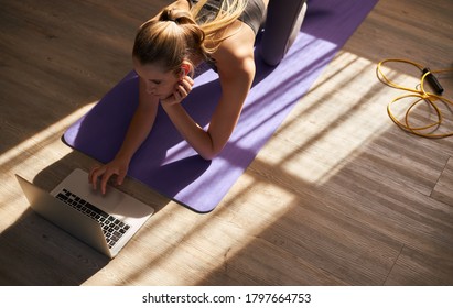 Young Woman Taking Part In Online Fitness Class In Front Of Laptop.