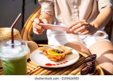 Young woman taking photo of dessert with smart phone for social media in restaurant while traveling - Powered by Shutterstock