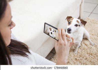 Young Woman Taking Photo Of Her Dog