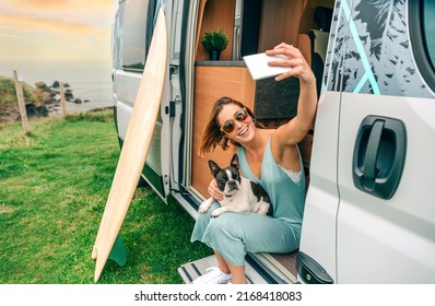 Young woman taking photo sitting with her boston terrier dog at the door of camper van - Powered by Shutterstock