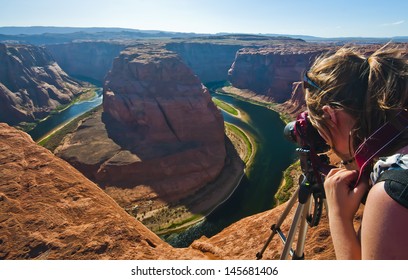 Young woman taking photograph of panoramic view of Horseshoe Bend at Utah, USA
