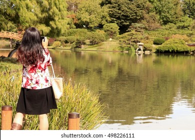 Young Woman Taking Photos Of A Lake With Her IPad In The Fall