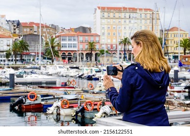 Young woman taking photos in a port of small boats