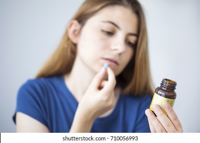 Young Woman Taking A Pill While Reading The Bottle