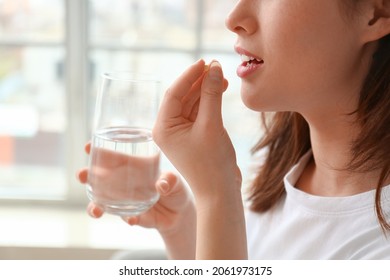 Young woman taking pills at home - Shutterstock ID 2061973175
