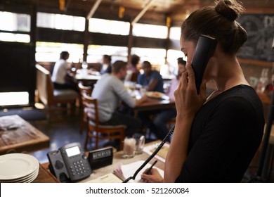 Young Woman Taking A Reservation By Phone At A Restaurant