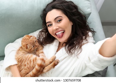 Young Woman Taking Selfie With Cute Funny Cat At Home