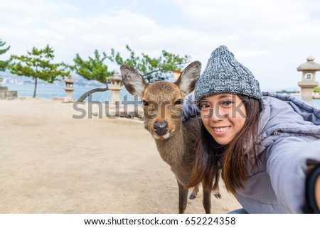 Young Woman taking selfie with deer in Itsukushima