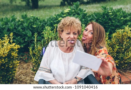 Woman taking selfie with older mother in wheelchair