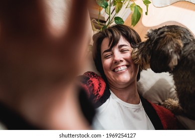 Young Woman Taking A Selfie With Mobile Fun Having Fun With Her Pet Dog Indoors At Home - Focus On Girl Face