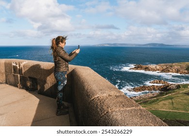 Young woman taking a selfie on a coastal lookout with panoramic ocean views at the tower of hercules - Powered by Shutterstock