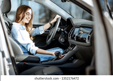 Young Woman Taking A Smart Phone From The Place Of Wireless Charging In The Modern Car In The City