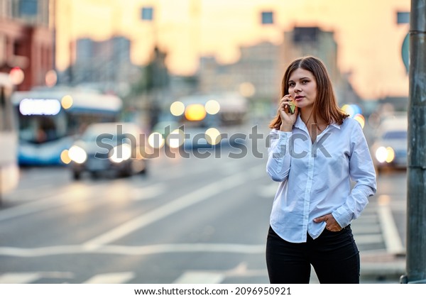Young\
woman is talking by handy on street with\
traffic.