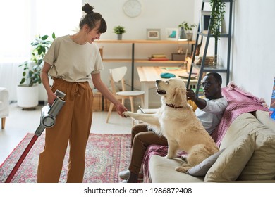 Young woman talking to dog during her housework at home