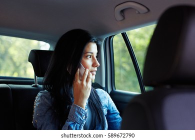 Young Woman Talking On Cell Phone And Sitting In Rear Of The Car