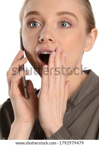 Young woman is talking on a cell phone. Surprise. Emotions of surprise. White isolated background. Studio shot. 