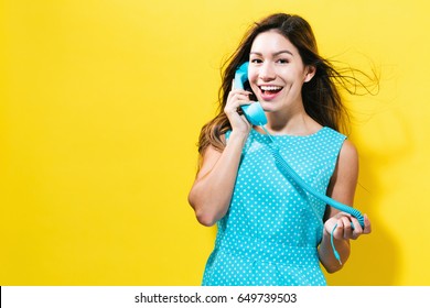 Young Woman Talking On Old Fashion Phone On A Yellow Background