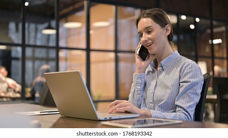 Young Woman Talking on Phone and Using Laptop - Shutterstock ID 1768193342