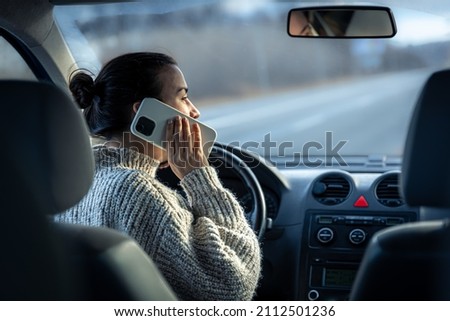 Young woman talking on the phone while driving a car.