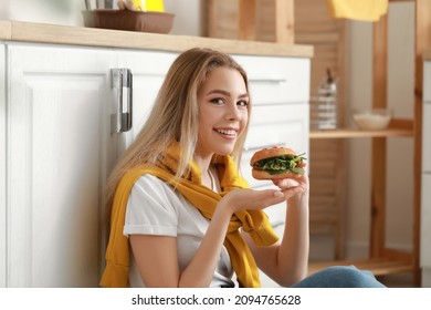 Young Woman With Tasty Vegan Burger In Kitchen