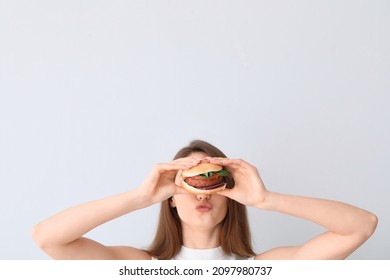 Young Woman With Tasty Vegan Burger On Light Background