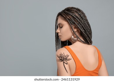 Young woman with tattoo of beautiful lotus flower on light grey background, space for text - Powered by Shutterstock