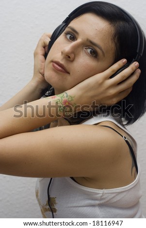 young woman with tattoos wearing headphones and listening the music