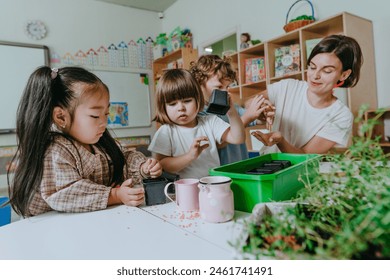 Young woman teacher with children in kindergarten plants a plant in a pot. Selective focus. - Powered by Shutterstock