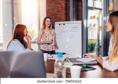 Young woman teaching English to adult students at language school - Shutterstock ID 704014162