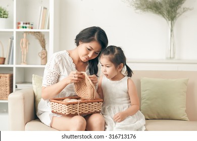 Young Woman Teaching Her Daughter How To Knit