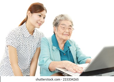 Young Woman Teaching Old Woman To Use Laptop