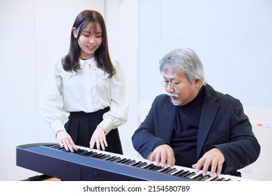 A young woman teaching the piano and a man teaching
