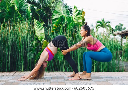 Young woman teaching yoga during luxury yoga retreat in Asia, Bali, meditation, relaxation, getting fit, enlightening, green grass jungle background, buddha statue
