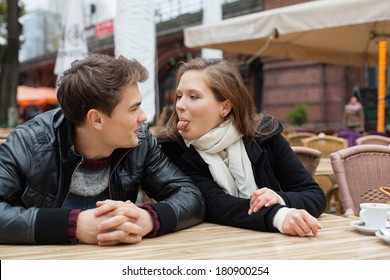 Young Woman Teasing Man While Sitting At Outdoor Restaurant