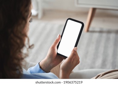 Young woman or teen girl hands holding smart phone with mockup white blank display, empty screen for social media app ads at home. Mobile applications technology concept, over shoulder close up view.