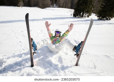 young woman or teenage girl in good mood while skiing fell and lies cheerfully in the snow. enjoying the moment, digital detox, positive thinking. Interesting active winter holiday, healthy lifestyle