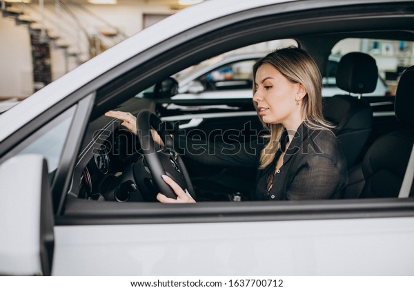 Young woman testing\
a car in a car showroom