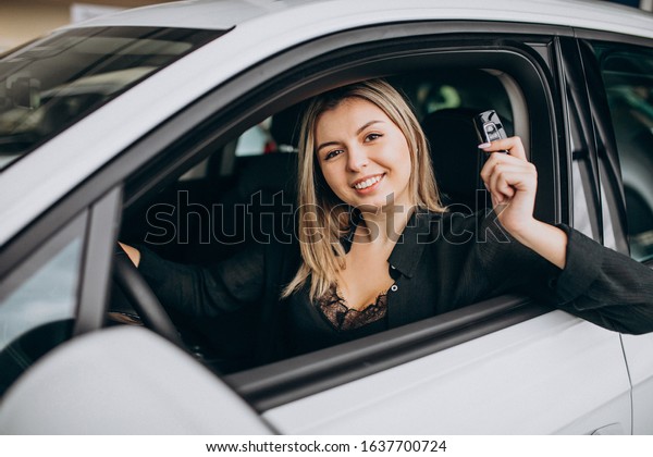 Young woman testing\
a car in a car showroom