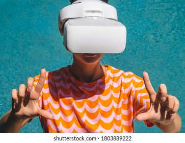 Young woman testing VR eyeglasses outside by the pool. Female in bright orange summer outfit wearing virtual reality headset during summer weather. Active modern futuristic leisure lifestyle concept - Powered by Shutterstock