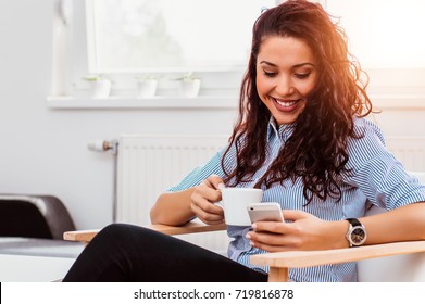 Young woman texting or using smartphone and drinking coffee in home office. - Powered by Shutterstock