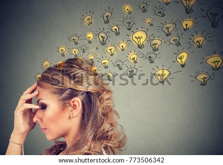 Young woman thinking with concentrated having many ideas with backdrop of burning lightbulbs. 