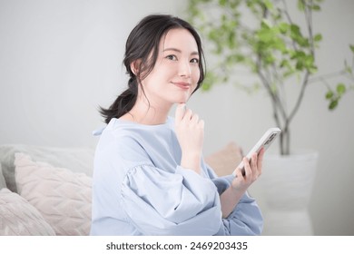 Young woman thinking with her phone in a beautiful living room Thinking Close-Up	 - Powered by Shutterstock