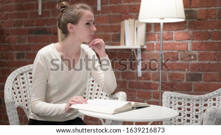 Young Woman Thinking and Reading Book at Home